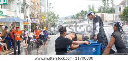 Thai young men in back of pickup truck getting splashed with water from people on roadside in celebrating Thai Songkran Water Festival to mark the start of the Thai new year.