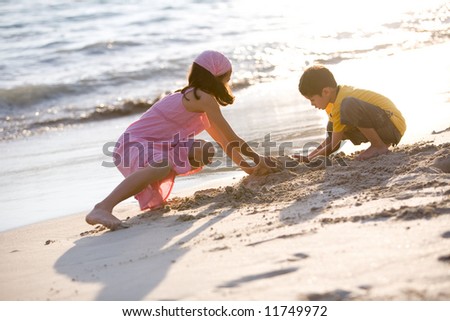 Two young children making sand castle together on a beautiful warm evening by the sea.