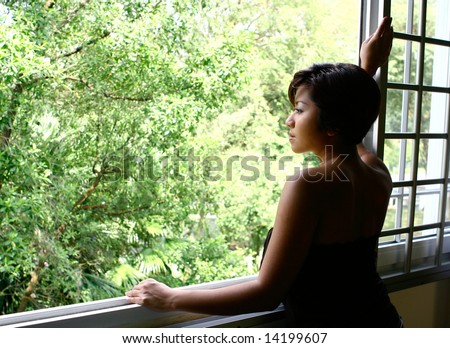 Young woman staring out of the window, contemplating life.