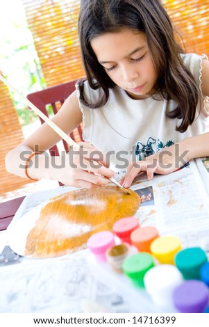 Young girl painting a paper plate in arts and craft.