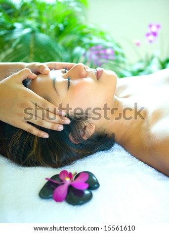 Young woman enjoying a holistic head massage in tropical spa.
