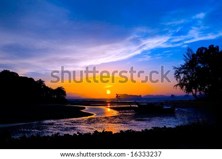 Beautiful sunset at resort bay with silhouettes against colorful sky.