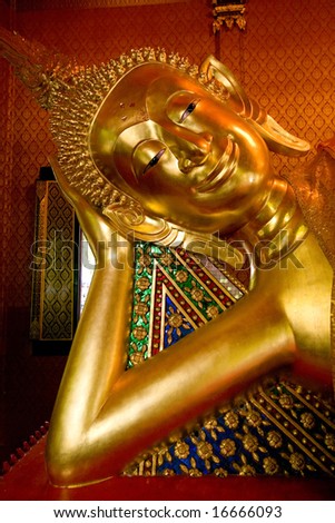 Statue of sleeping Buddha covered in gold paint and gold leaf in a local Thai temple