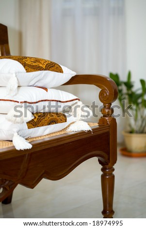 Three beautiful cushion on wooden indoor seat.