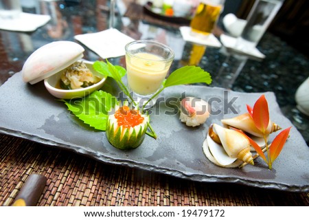 Plate of traditional Japanese appetiser made out of raw fish, rice, fish eggs, warm tofu and steamed snails.