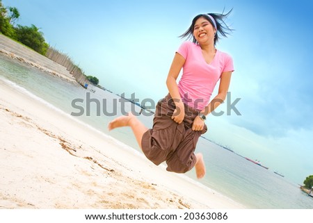Young Asian woman jumps up high on tropical beach