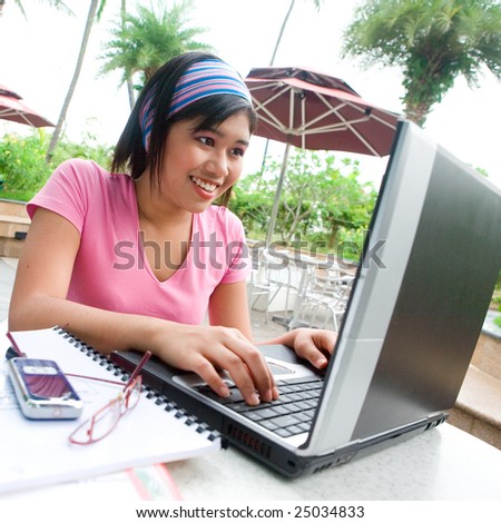 Young Asian student appearing excited while using her notebook computer