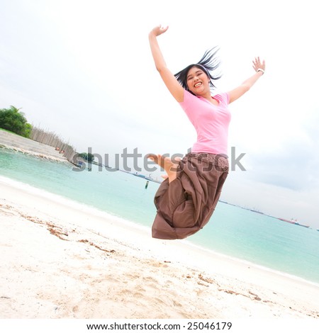 Young girl jumps up high in the air, by the beach
