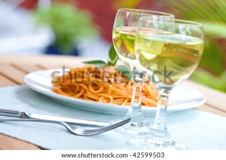 Outdoor setting, a plate of spaghetti with two glasses of wine
