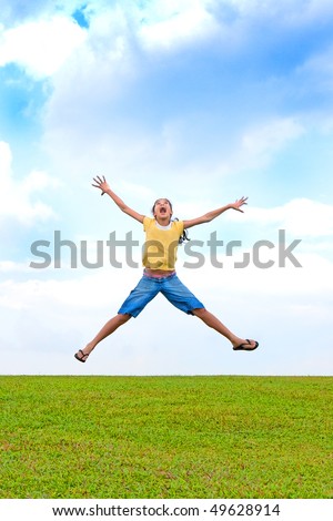 Young girl jumping in the air, over green field