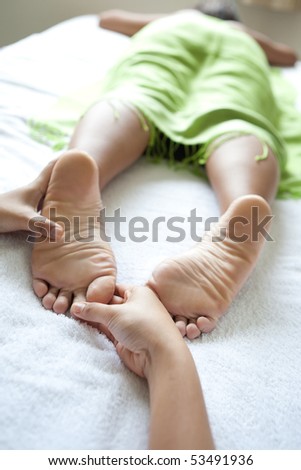 Woman foot reflexologist giving woman client a foot reflexology