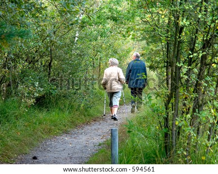 Middle aged people, seniors, man and woman talking a walk in the forest, sunny autumn day.