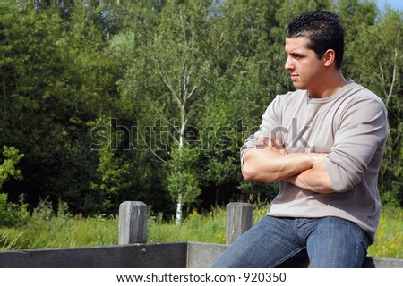 An attractive young man on his lunch hour, taking a rest in the park. Looking pensive to something right from him.