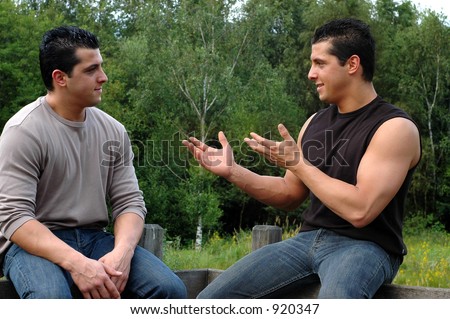 Two attractive young men, twins on their  lunch hour, taking a rest in the park, having a conversation. This is a trick photo of the same person twice.