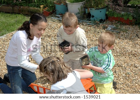 Toddlers and young girl playing with toy in garden.  Youth concept.