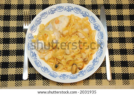 Pasta with fish, lobster sauce on top of place mat.  Culinary, food concept.