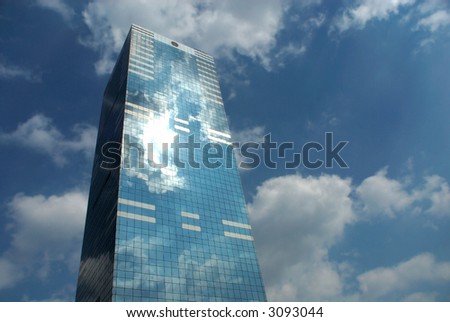 office building, skyscraper against dramatic blue cloudy sky. Circle on top is window, not logo.