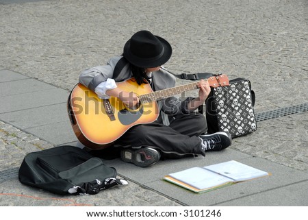 Female street performer, playing the guitar in paris on place pompidou in france