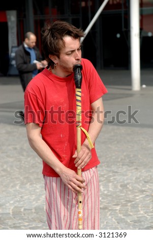 Male street performer, playing the flute in paris on place pompidou in france. focus on flute