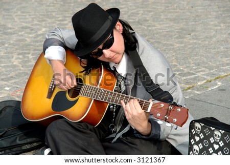 Female street performer, playing the guitar in paris on place pompidou in france
