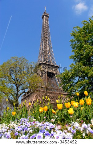 Spring in Paris, france, the eiffel tower against a vibrant blue spring sky with tulips in foreground. HDR, high dynamic range image.