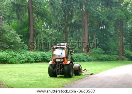 Lawn mower machine mowing the lawn in a formal garden.  Landscaping, gardening concept