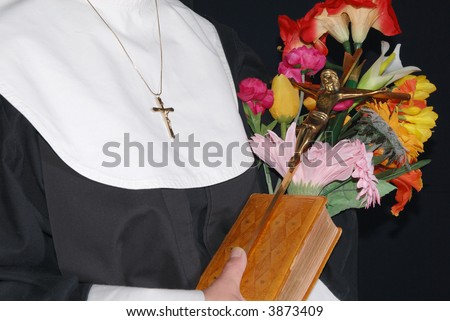 Middle aged devout nun  holding on to bible, cross and flowers.  Religion, christianity, lifestyle concept