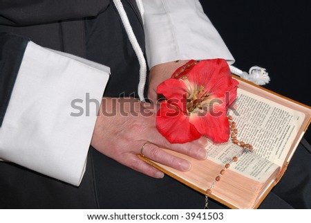 Nun hands resting on the book of faith, the bible, rosary and flower in hand.  Religion, christianity, lifestyle concept