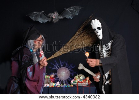 Halloween witch and skeleton offering candy, sweets, trick or treat, holiday, happiness, food concept