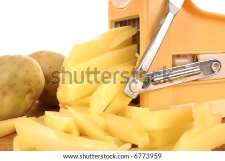 Making fresh fries, potatoes being pushed into fries cutter, peeled and un-peeled potato on the side, white background