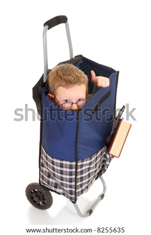 Eight year young boy in shopping bag, cart.  White background, studio shot.
