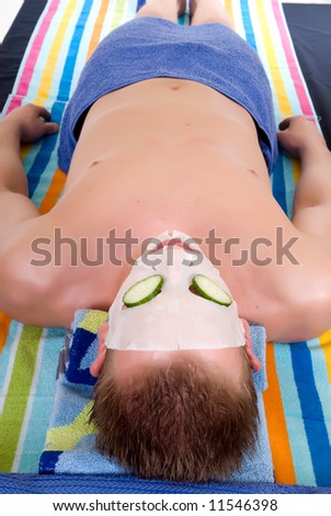 Attractive handsome young man with face mask in spa center. White background,