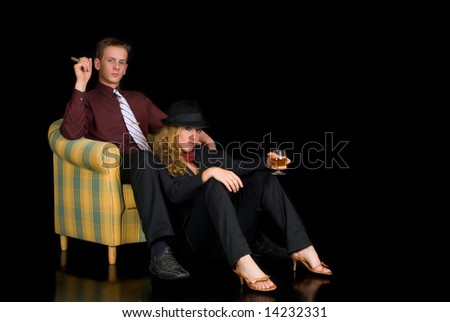 Attractive young classy couple, formal clothing, woman wearing suit and bow tie.  Studio shot, black background.