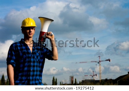 Young handsome male construction worker with megaphone against blue sky
