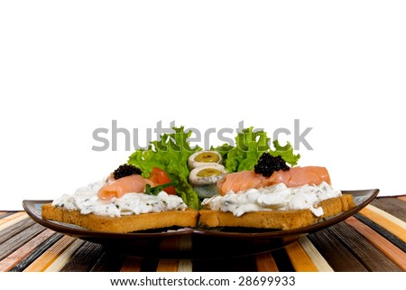 Gourmet cheese smoked salmon toast, garnished with caviar, anchovies, olives and salad.  Studio shot.