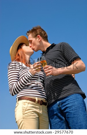 Young handsome couple in love with champagne against blue sky.