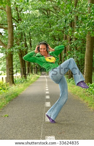 Attractive young woman with headset in nature setting. Slight motion blur on lower body.