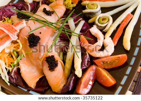 Gourmet smoked salmon dish, garnished with shrimp, caviar, anchovies, olives and vegetables.  Studio shot.