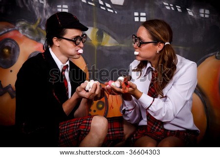 Young Halloween couple, female  and male with English boarding school student outfit.    Studio shot, painted background.