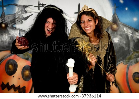 Young Halloween couple, female witch and man with sinister costume.    Studio shot, graffiti  background.