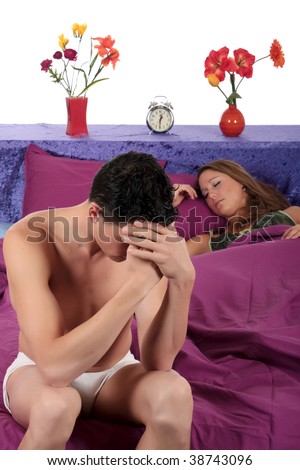 young  couple on bed in bedroom, man having a depression moment while wife is sleeping.  Studio.
