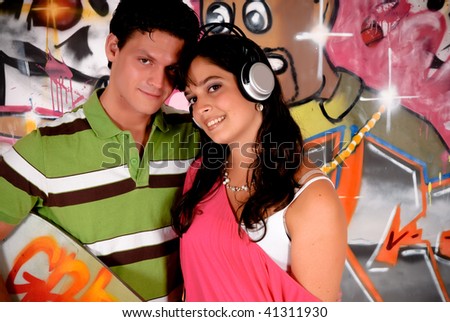 Two teenagers in love in front of graffiti wall, urban setting.  Studio shoot.