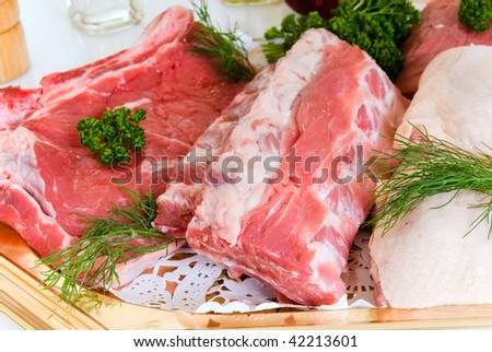 Diversity display of meat on dish, t-bone steak, hamburger, chicken leg, tenderloin roast, ribs .  Studio shot.
