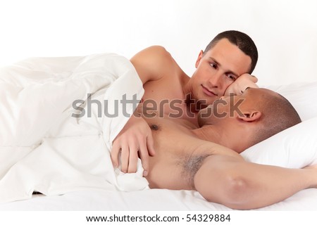 Attractive young mixed ethnicity gay, homosexual couple, Caucasian and African American men in the bedroom, grooming.  Studio, white background.