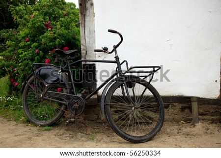 Old baker delivery bicycle parked against old house wall.  Rural live, scene