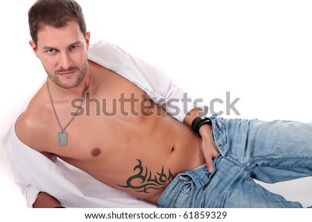 Young seductive caucasian man lying down with the hand in his pants and