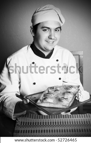 handsome young chef in the professional manner in the living room with cake from pears