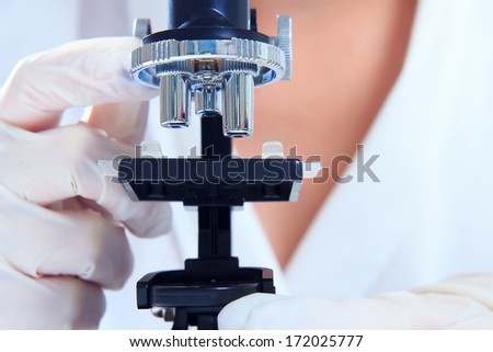 The doctor, a researcher works with a microscope. Closeup