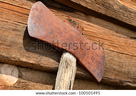 Old double headed logging axe on a wood cabin wall