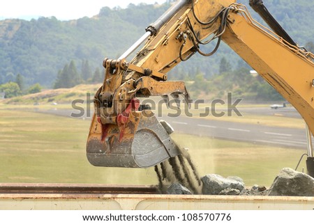 A large tracked hoe or excavator working at a construction site to extend an airport runway.